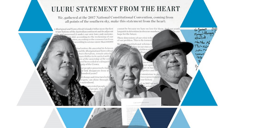 Three people stand in front of the "Uluru Statement From The Heart" text, surrounded by blue and gray geometric triangles, conveying unity and purpose.